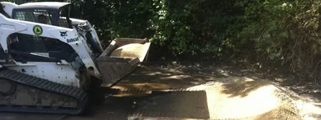 Skid steer grading a gravel driveway during construction