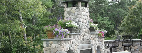 Fieldstone outdoor fireplace with planters and patio seating